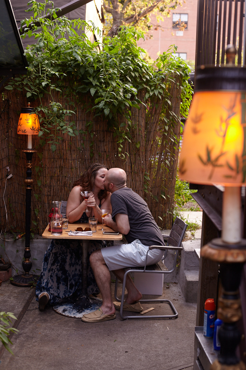 The Good Fork, back patio, a couple kisses as they drink a glass of wine in Red Hook, Brooklyn, New York