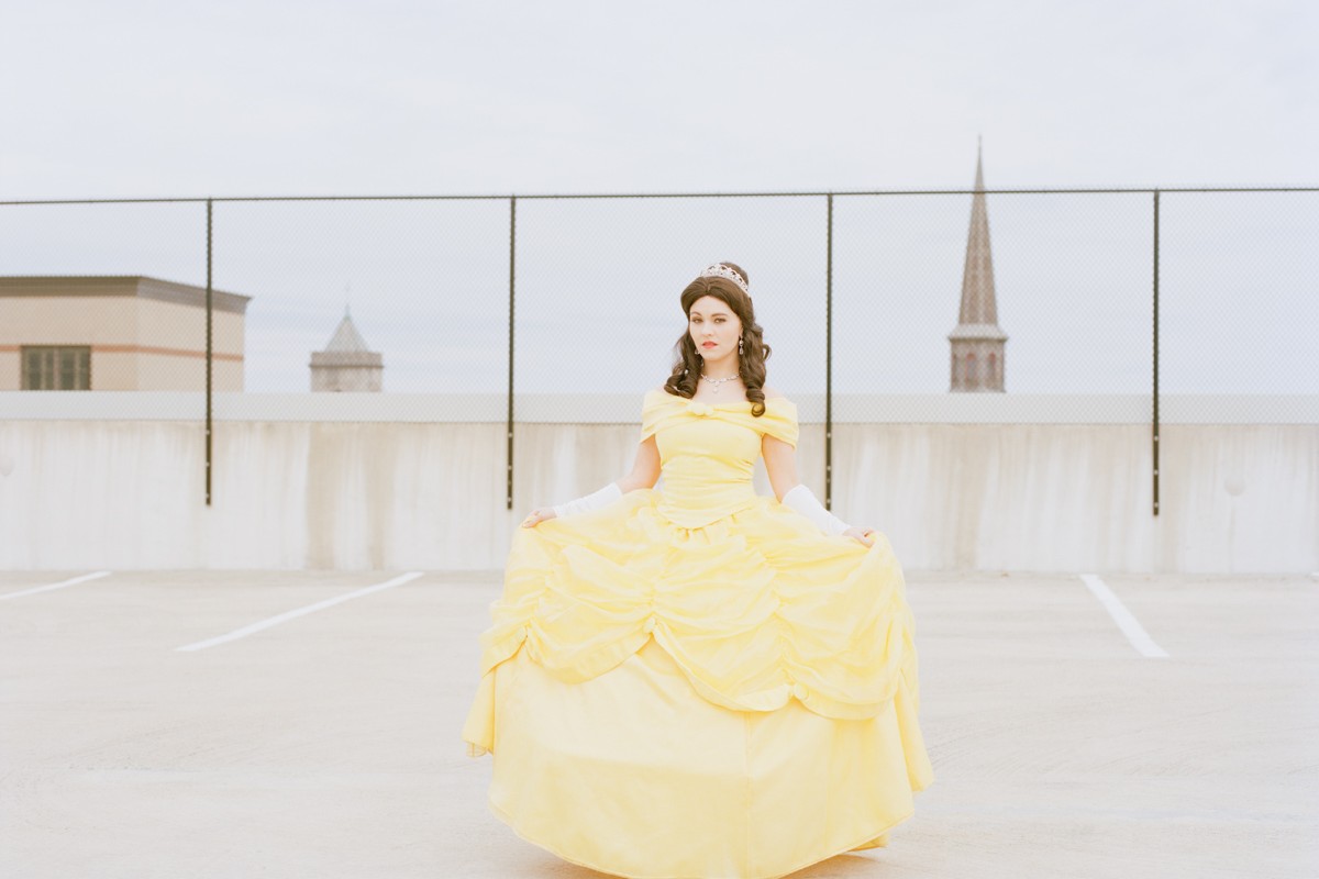 Refinery29 Real Life Disney Princesses Portrait Ordinary Woman Impersonates Works Disney Princess Belle Yellow Dress Empty Parking Garage Rooftop Downtown Church Steeple New Jersey