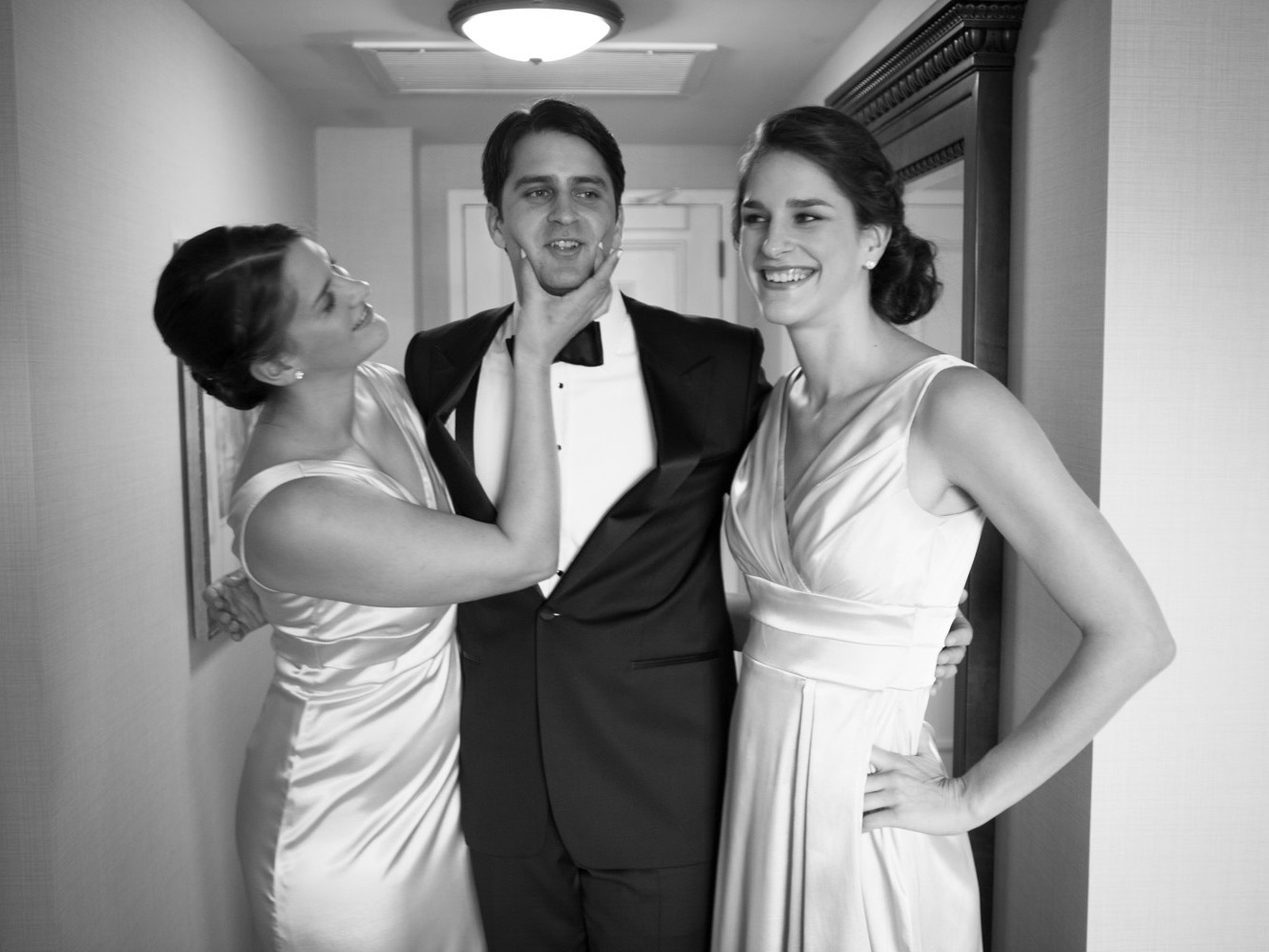 Stylish modern wedding ceremony held at posh, high-end, luxurious Four Seasons Hotel in downtown Philadelphia. Groom's sisters in matching white gowns tease their brother before the wedding ceremony.