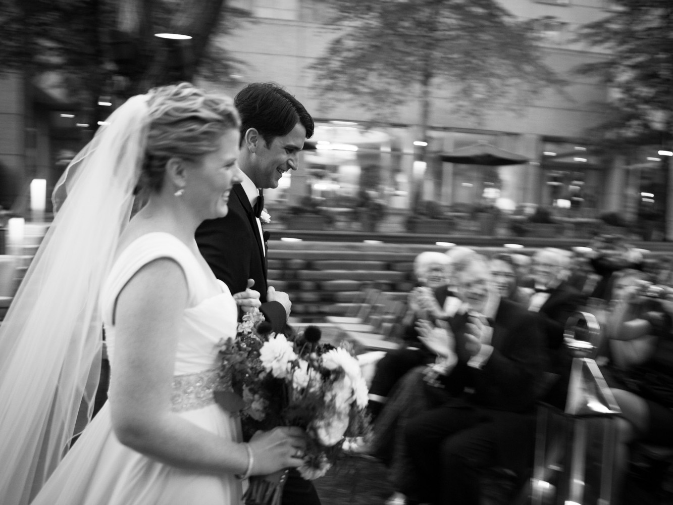 Stylish modern wedding ceremony held at posh, high-end, luxurious Four Seasons Hotel in downtown Philadelphia. Bride and groom hold hands listening to the pastor officiant during wedding ceremony.