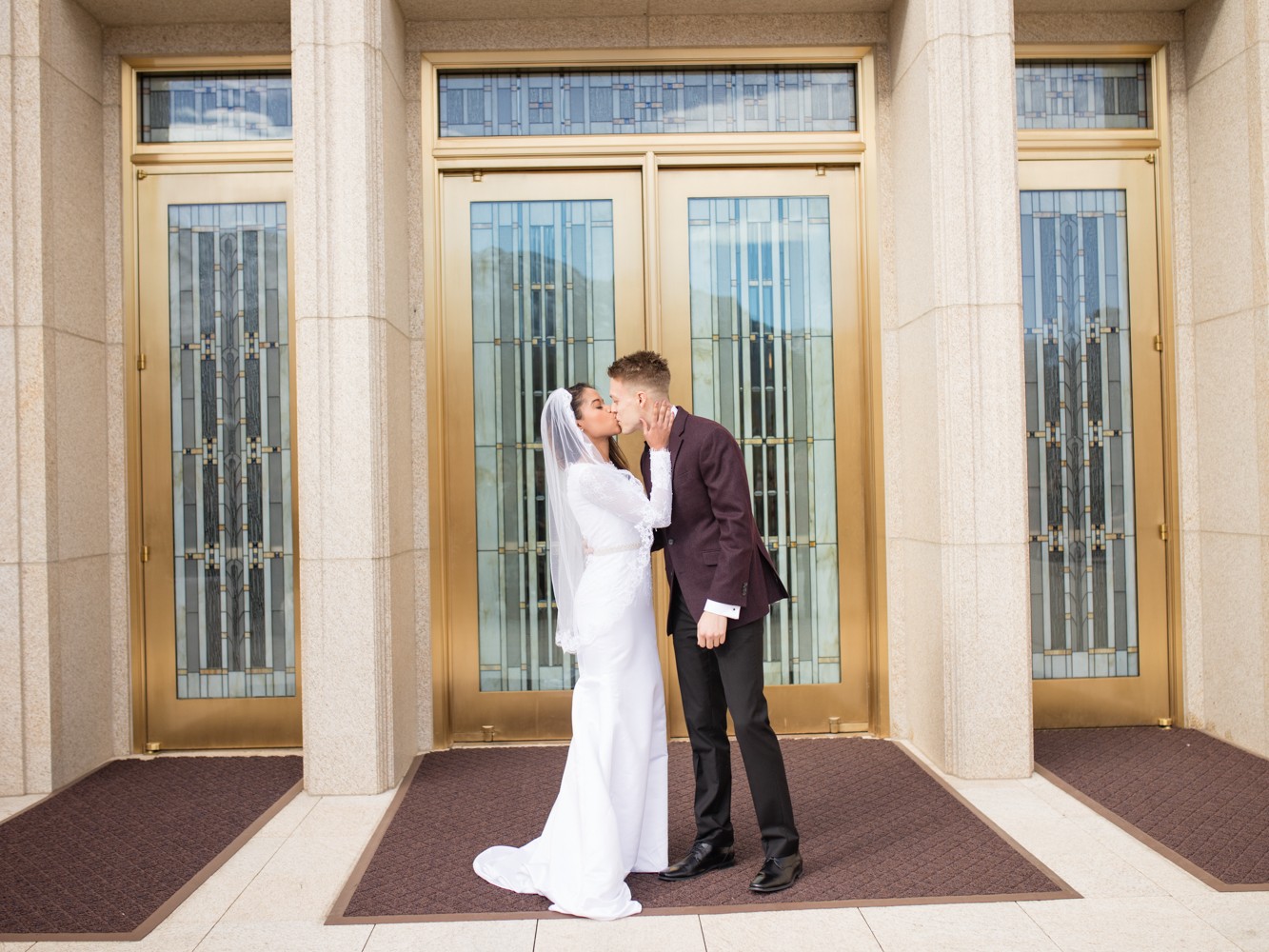 Portrait of bride and groom kissing outside the LDS Ogden Temple after the interracial couple's wedding ceremony in Utah.