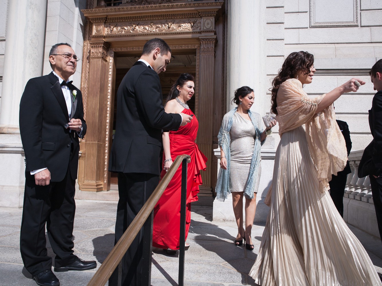 A Muslim couple have an opulent wedding ceremony at the Society Room with large family and many friends at beautiful hotel in Hartford, Connecticut. Groom and family stand outside the historic state building.