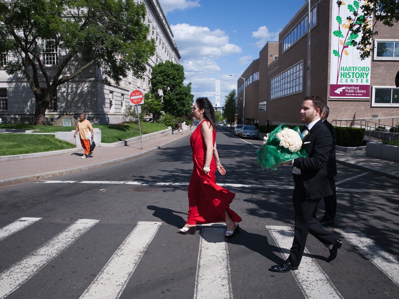 A Muslim couple have an opulent wedding ceremony at the Society Room with large family and many friends at beautiful hotel in Hartford, Connecticut. Groom's mother in elegant red gown walks across the street.