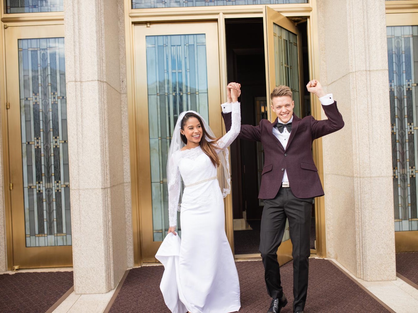 Portrait of bride and groom kissing outside the LDS Ogden Temple after the interracial couple's wedding ceremony in Utah.