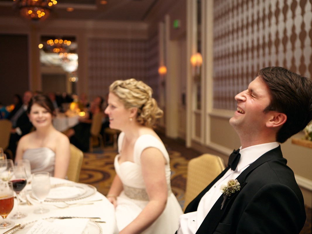 Stylish modern wedding ceremony held at posh, high-end, luxurious Four Seasons Hotel in downtown Philadelphia. Groom laughs loudly during speeches at wedding.