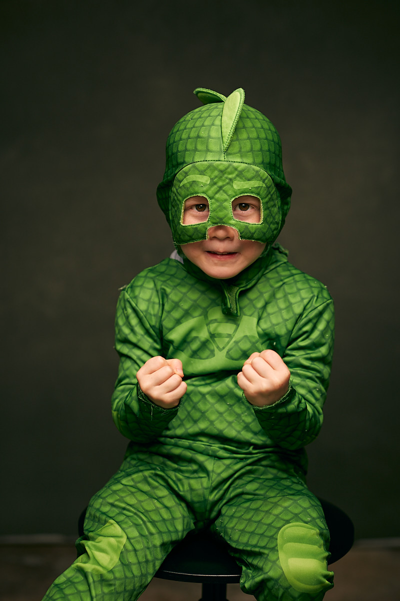 Portrait of cute young bo clenching fists in green dinosaur costume in studio - Dallas Portrait Photographer